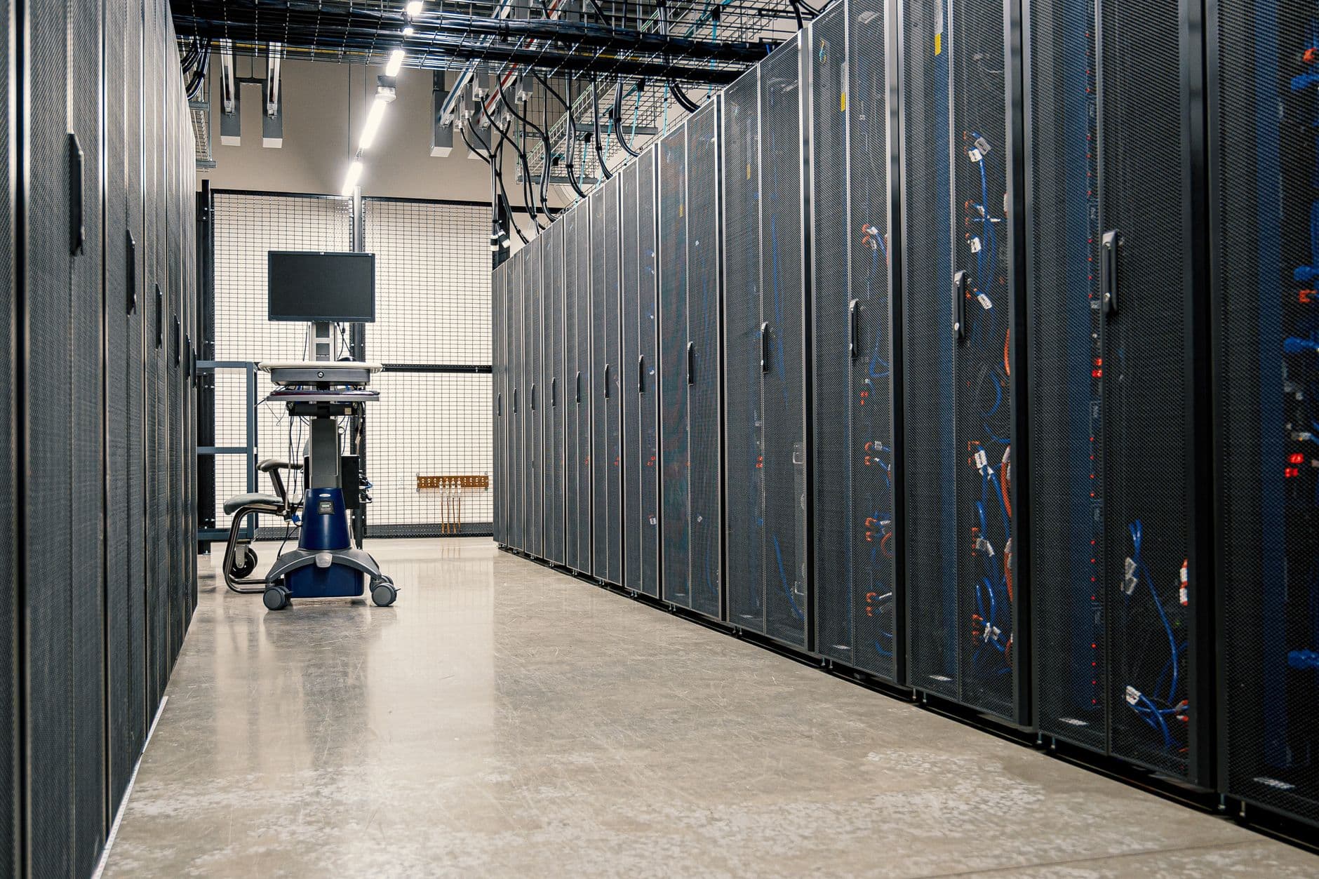 Rows of server cabinets in a modern data center hall illustrating the cooling load that drives CRAC, CRAH, and chiller refrigerant strategy under EPA 40 CFR Part 84 Subpart C