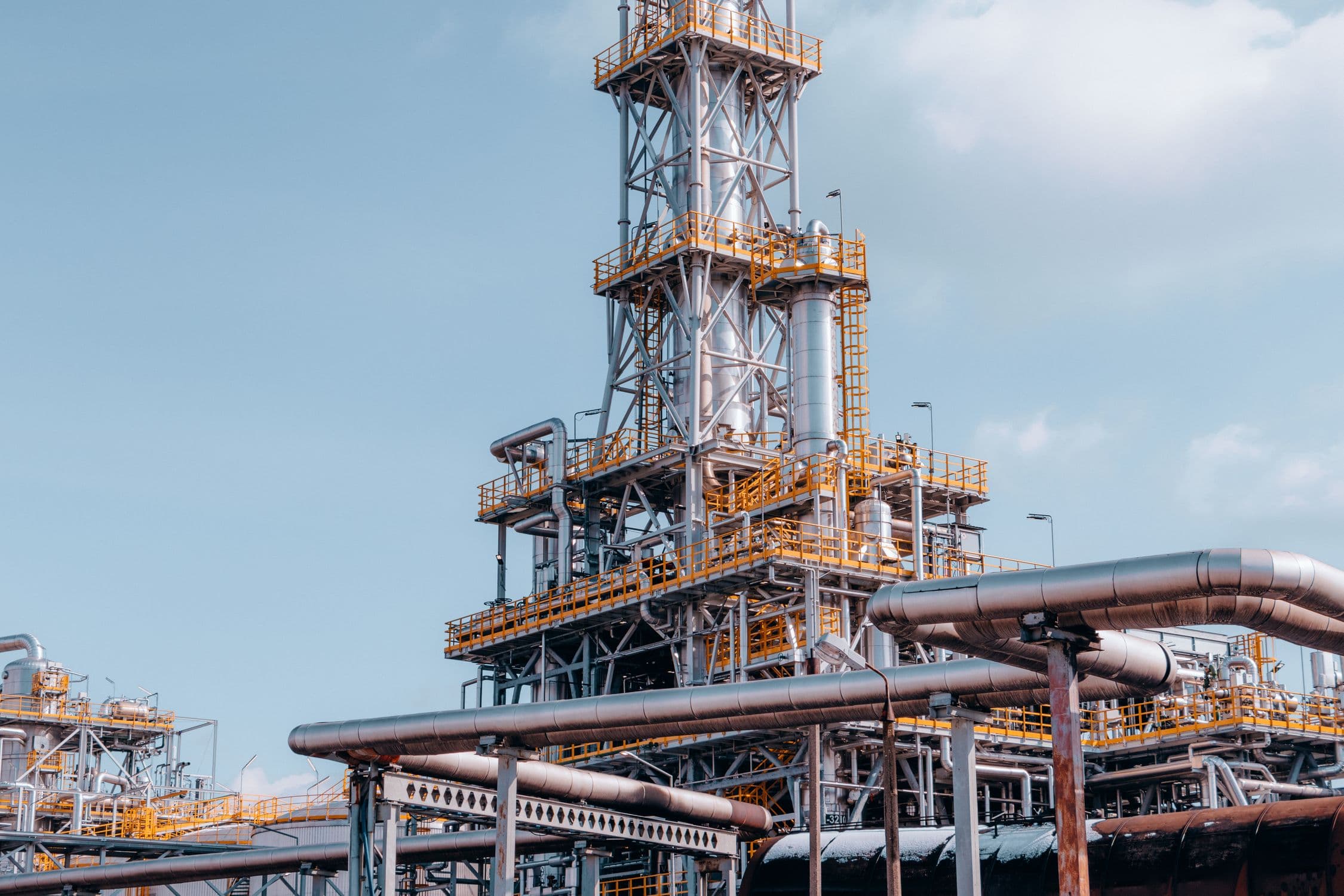 Wide view of a large industrial refinery and process plant with intricate pipework and storage vessels, representing the kind of facility that operates industrial process refrigeration systems subject to 40 CFR Part 84 Subpart C
